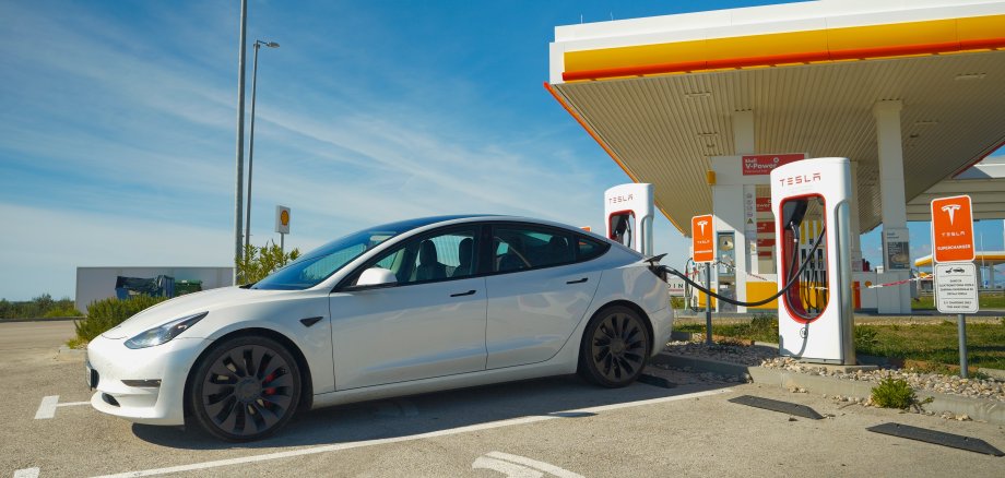 Elektrofahrzeug lädt an einer Tankstelle mit Ladestationen