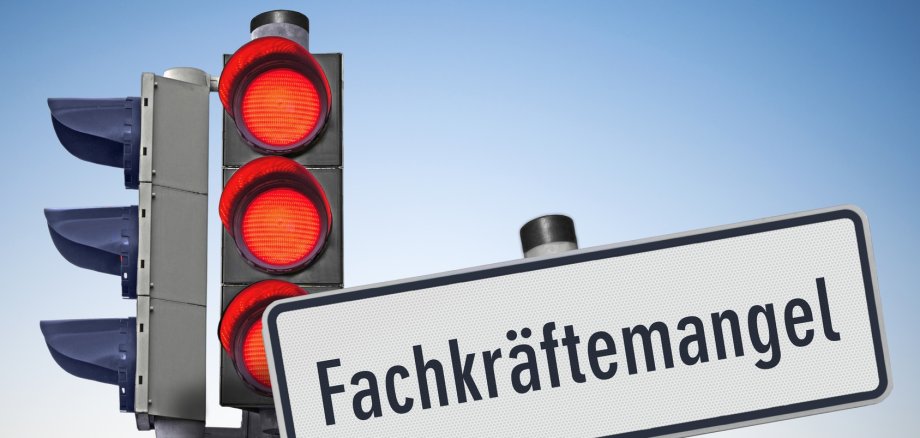 Drei Ampel die Rot anzeigen davor ein Schild: Fachkräfte mangel