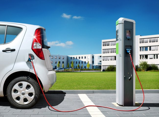 Elektroauto an Stromtankstelle vor Bürogebäude