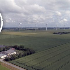 Luftbild aus dem Friedrich-Wilhelm-Lübke-Koog, auf dem ein teilnehmendes Gebäudes der Wind-und-Wärme-Modellregion und Teile des Bürgerwindparks zu sehen sind